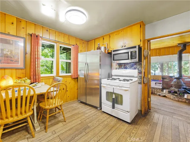 a large kitchen with stainless steel appliances granite countertop a stove a sink dishwasher and white cabinets with wooden floor