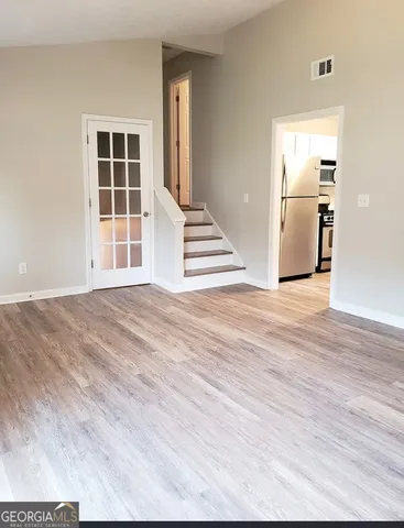 a view of a livingroom with wooden floor and kitchen space
