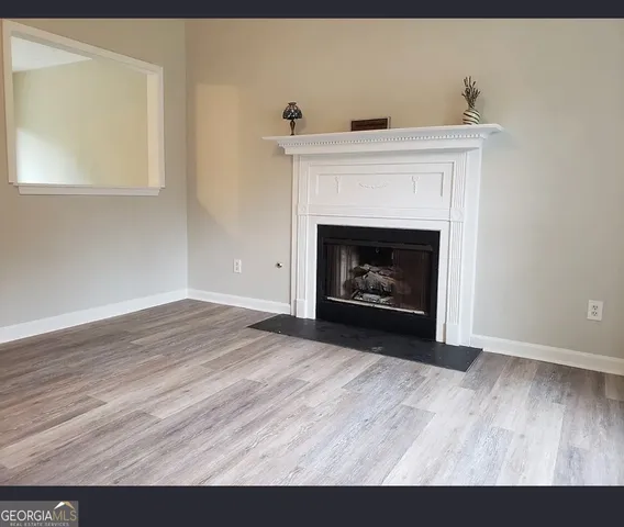 a view of an empty room with wooden floor and a fireplace