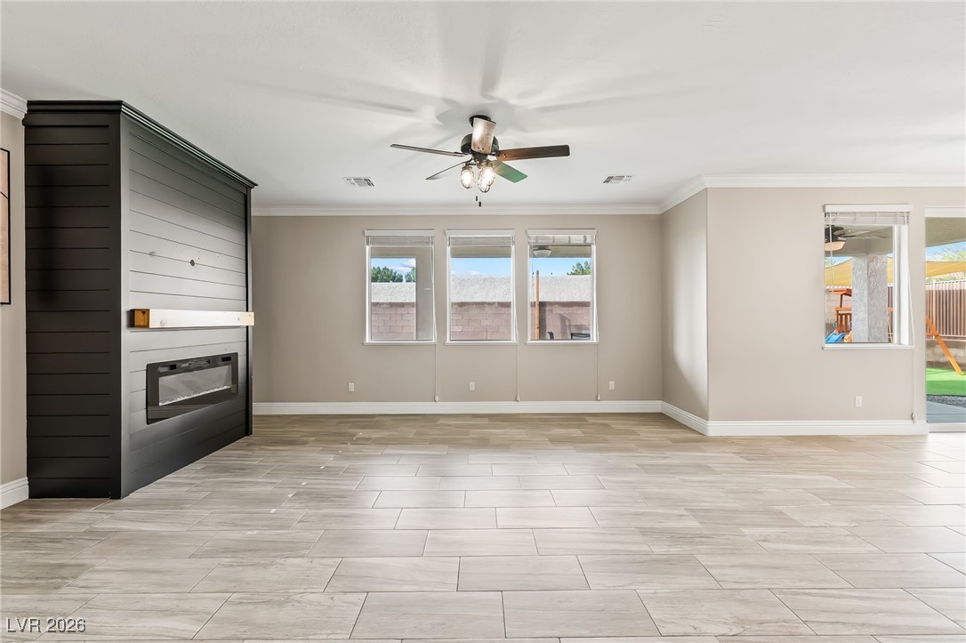 3807 Chapels Royal Street Laughlin, NV 89029 - Photo 11 of 62 Unfurnished living room with crown molding, a large fireplace, and a ceiling fan