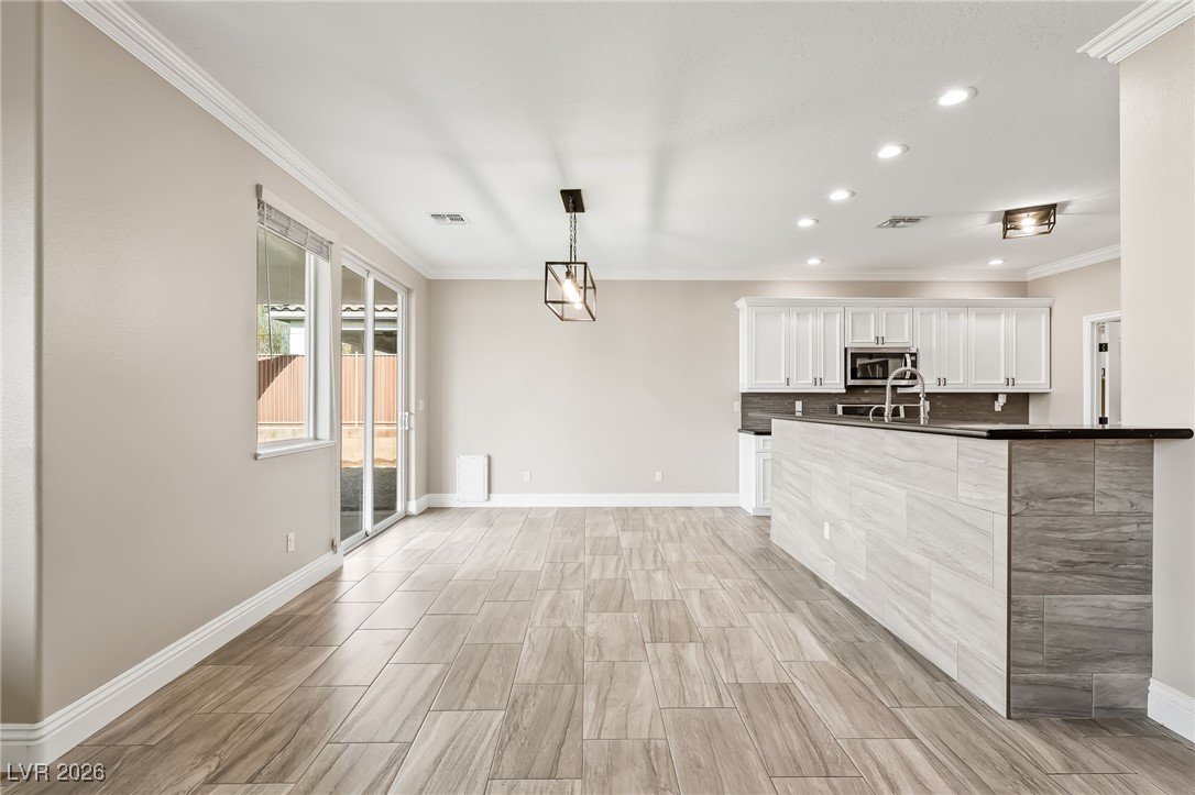 3807 Chapels Royal Street Laughlin, NV 89029 - Photo 14 of 62 Kitchen featuring white cabinets, crown molding, wood tiled floors, pendant lighting, and recessed lighting