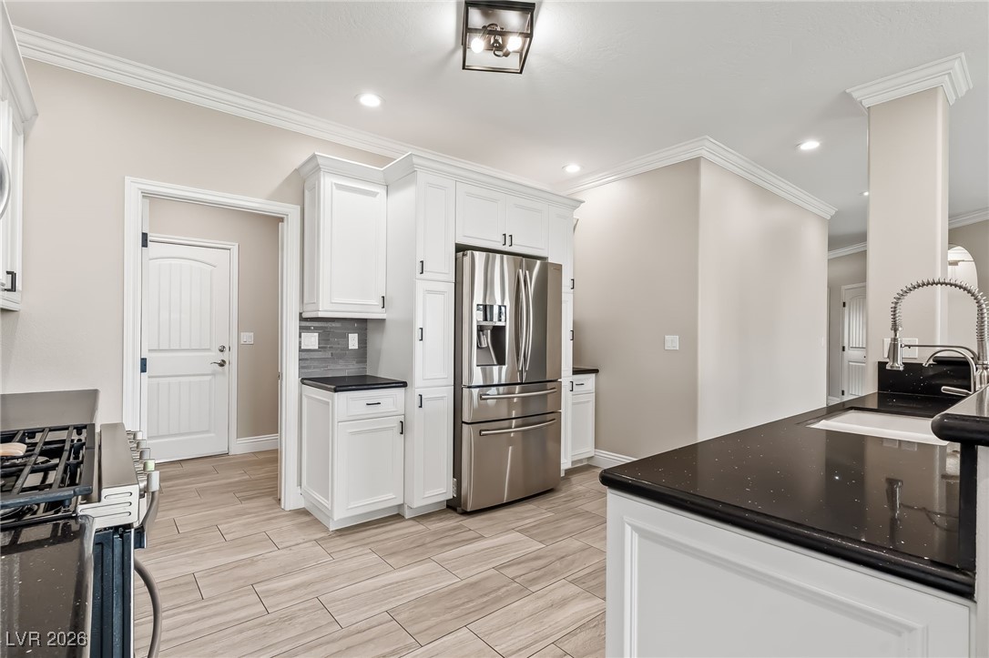 3807 Chapels Royal Street Laughlin, NV 89029 - Photo 18 of 62 Kitchen with stainless steel refrigerator with ice dispenser, range with gas cooktop, white cabinetry, recessed lighting, and decorative backsplash