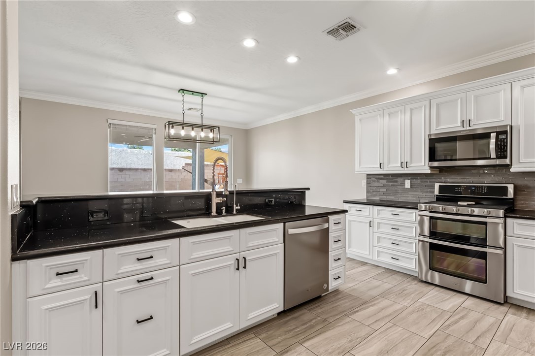 3807 Chapels Royal Street Laughlin, NV 89029 - Photo 20 of 62 Kitchen featuring stainless steel appliances, recessed lighting, white cabinets, crown molding, and decorative light fixtures