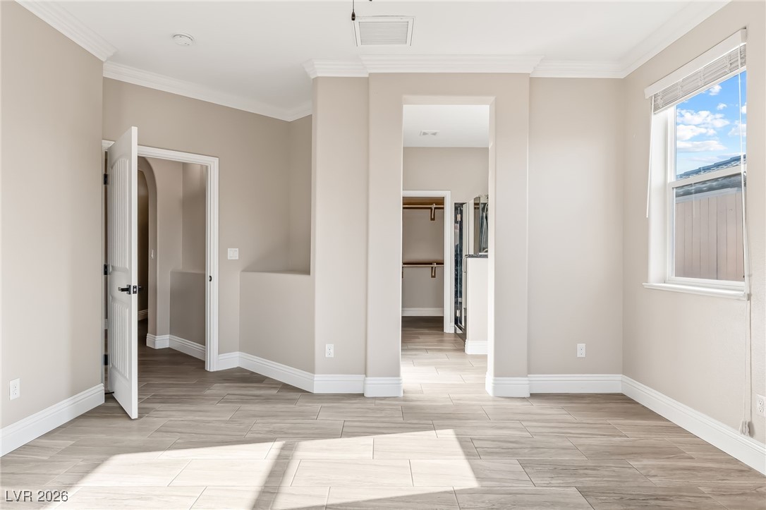 3807 Chapels Royal Street Laughlin, NV 89029 - Photo 23 of 62 Primary bedroom featuring a walk in closet, wood tiled floors, and crown molding