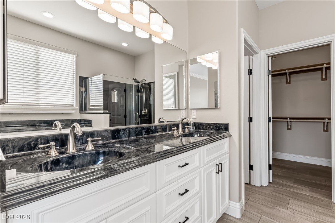 3807 Chapels Royal Street Laughlin, NV 89029 - Photo 24 of 62 Primary Ensuite Bathroom with a shower stall, double vanity, wood finish floors, and plenty of natural light
