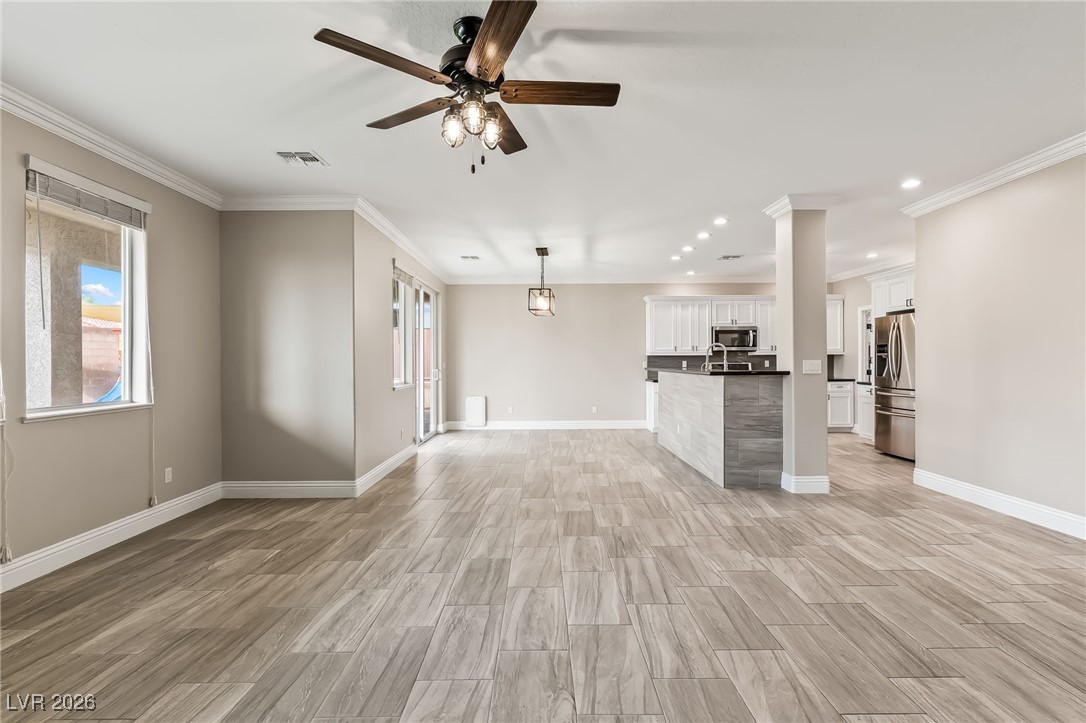 3807 Chapels Royal Street Laughlin, NV 89029 - Photo 10 of 62 Unfurnished living room featuring a ceiling fan, healthy amount of natural light, wood finish floors, crown molding, and recessed lighting