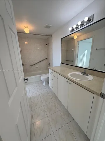 a bathroom with a granite countertop toilet sink and mirror