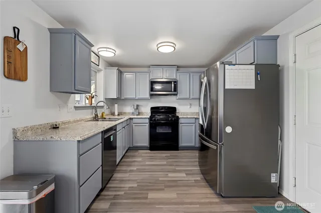 a kitchen with granite countertop a refrigerator stove top oven and sink