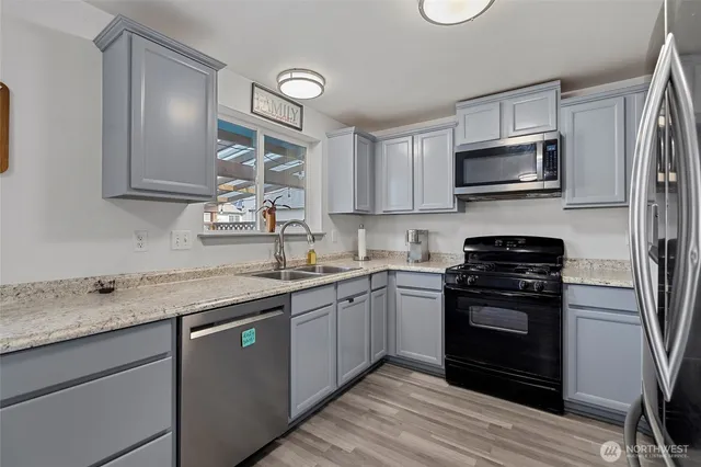 a kitchen with stainless steel appliances granite countertop a stove top oven a sink dishwasher a refrigerator and cabinets with wooden floor