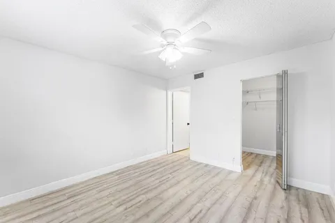 an empty room with wooden floor and fan