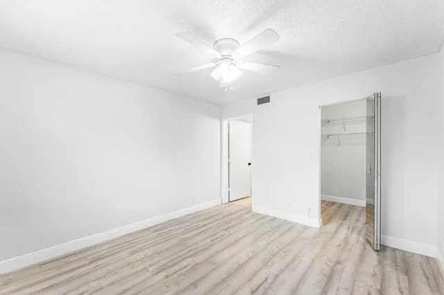 an empty room with wooden floor and fan