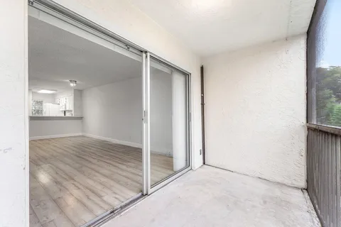 an empty room with wooden floor and a bathroom view