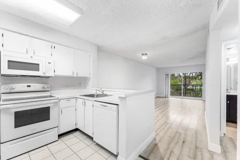 a view of a kitchen with white cabinets and wooden floor
