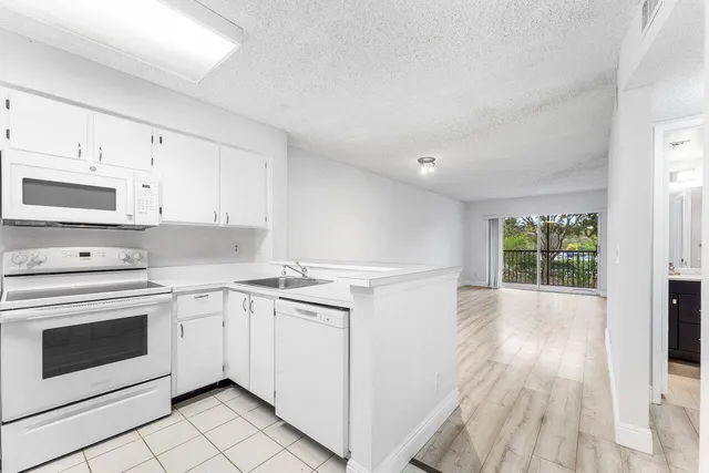 a view of a kitchen with white cabinets and wooden floor