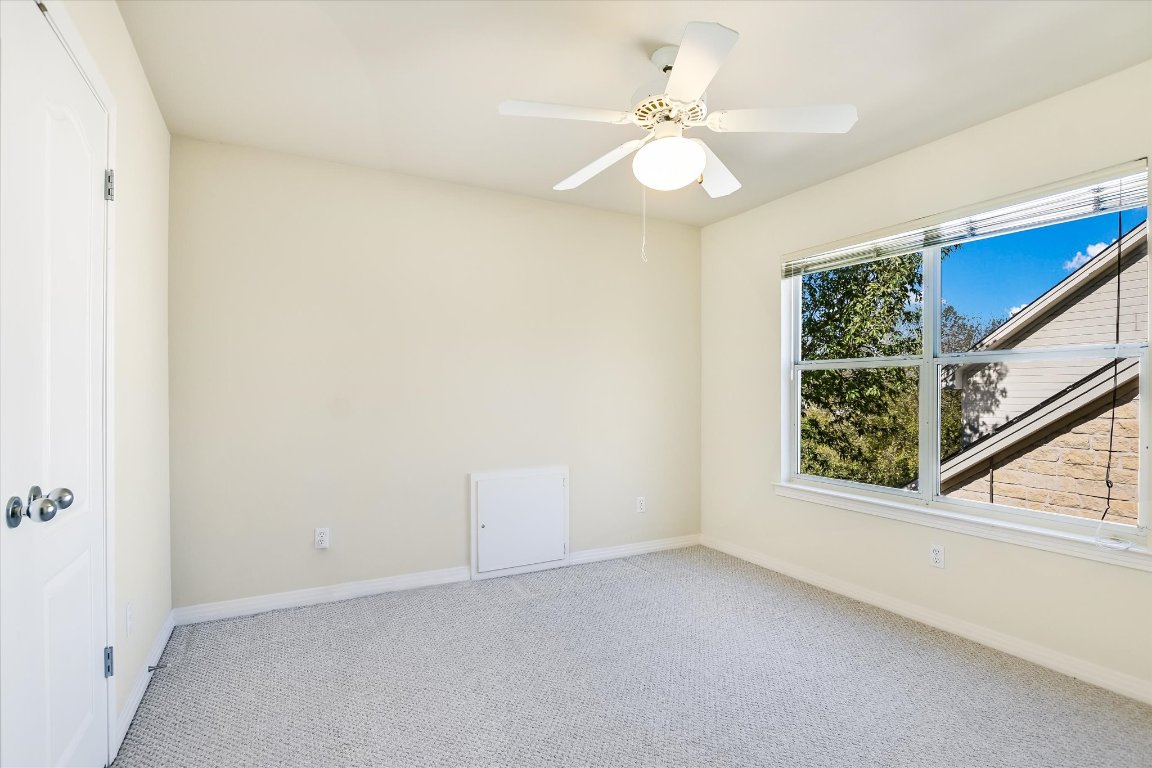 4819 Spicewood Springs Road Austin, TX 78759 - Photo 13 of 20 an empty room with a chandelier fan and windows