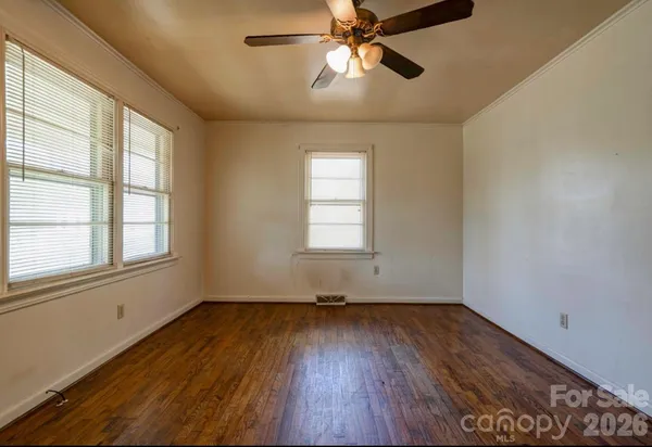 a view of empty room with wooden floor and fan
