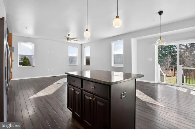 a kitchen with stainless steel appliances granite countertop a sink a wooden floor and a large window