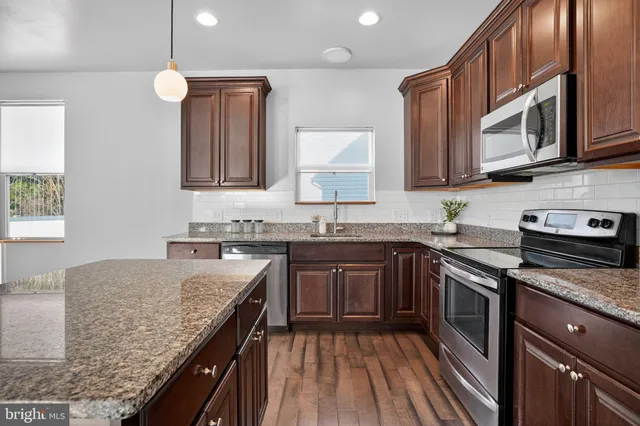 a kitchen with stainless steel appliances granite countertop sink stove microwave and cabinets
