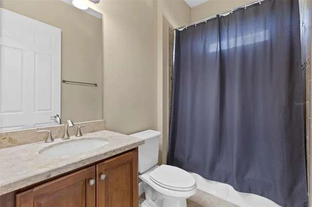 a bathroom with a granite countertop sink toilet and a mirror