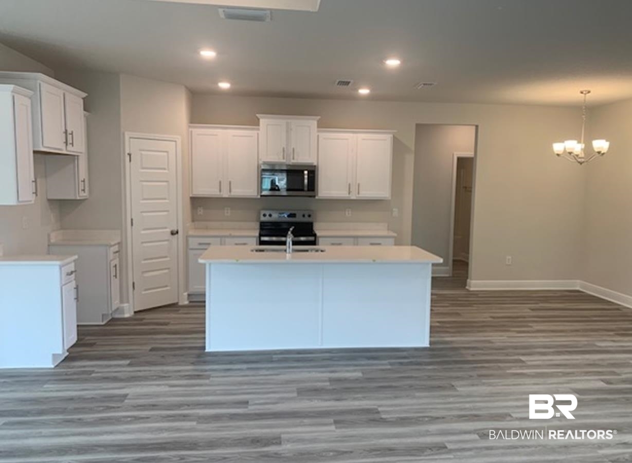 12904 Grand Rpds Road Fairhope, AL 36532 - Photo 20 of 34 Kitchen featuring light hardwood / wood-style floors, an inviting chandelier, white cabinets, an island with sink, and appliances with stainless steel finishes