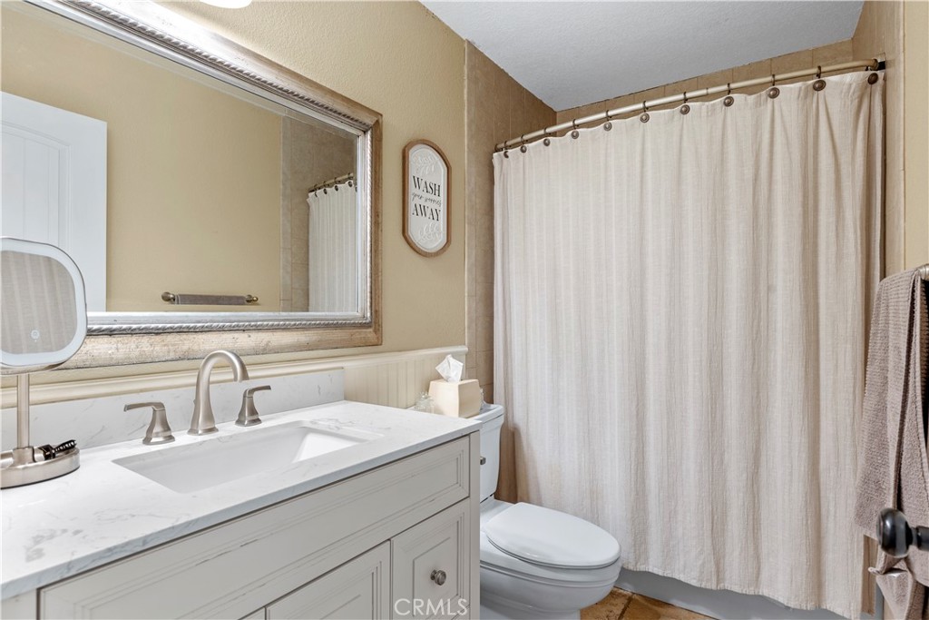 28841 Delaware Drive Tehachapi, CA 93561 - Photo 18 of 36 a bathroom with a granite countertop sink a toilet and a mirror