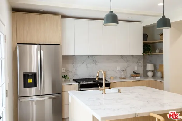 a kitchen with stainless steel appliances granite countertop a refrigerator a stove and a sink with wooden floor