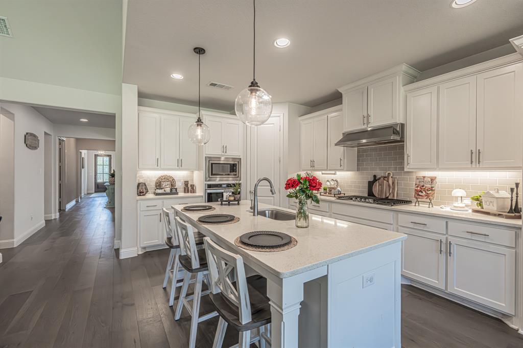1610 Gardenia Street Prosper, TX 75078 - Photo 10 of 36 a kitchen with a sink a stove a dining table and chairs