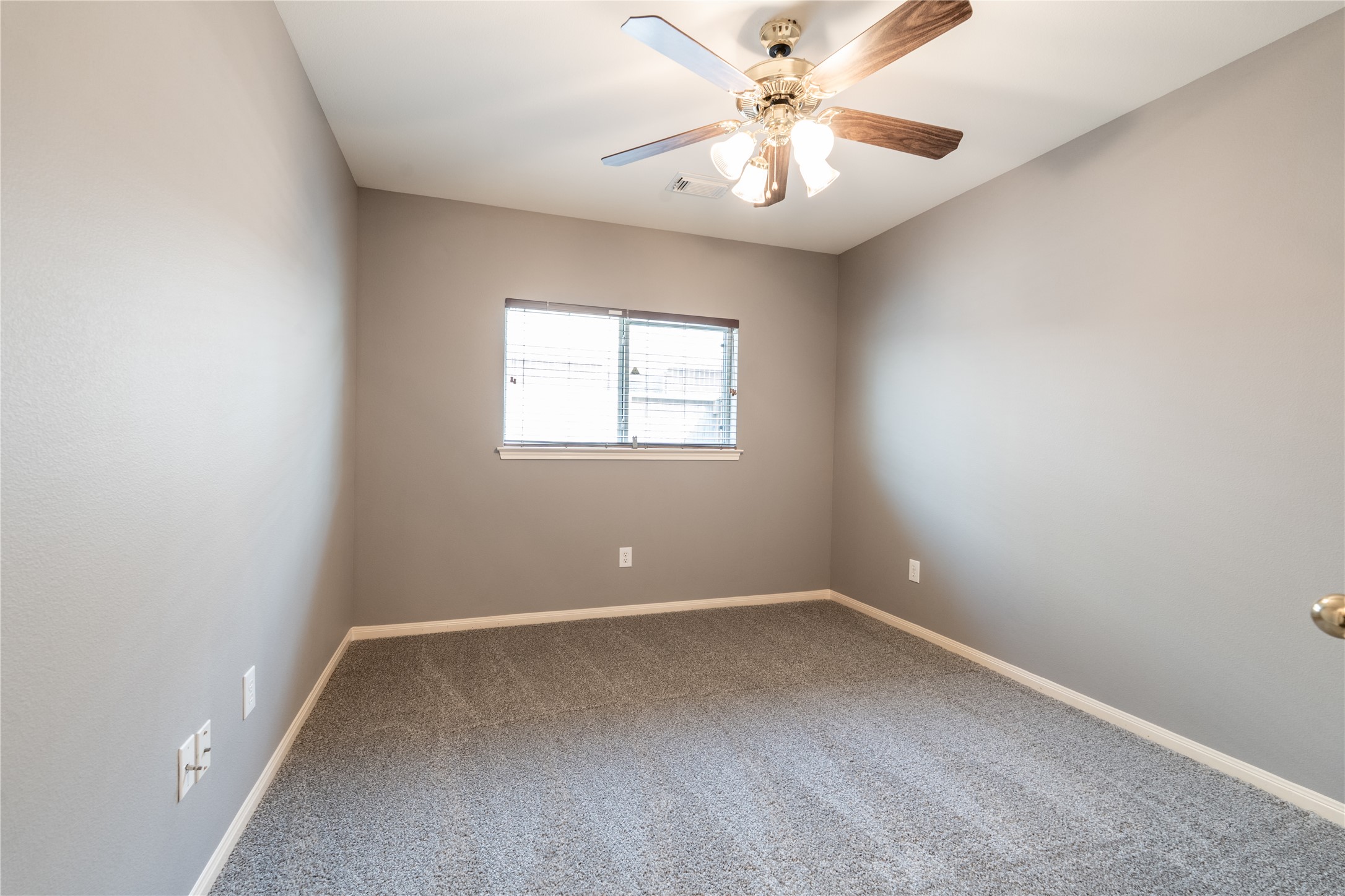 10619 Crownsedge Drive Spring, TX 77379 - Photo 20 of 38 This room features neutral gray walls, a ceiling fan with lights, and a window allowing natural light. It's carpeted, creating a cozy atmosphere.