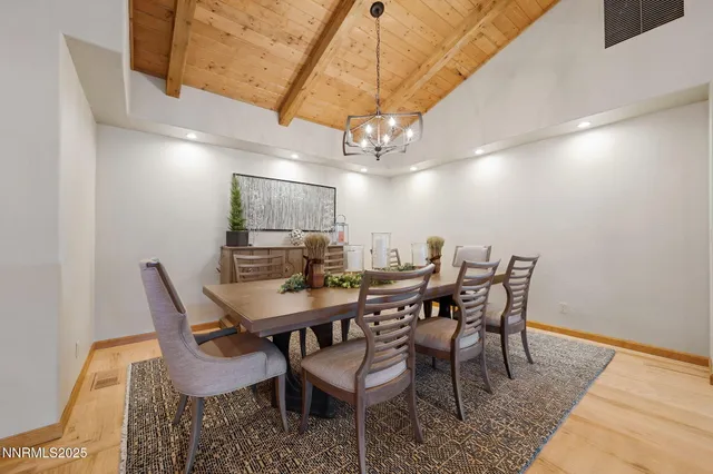 a kitchen with stainless steel appliances kitchen island granite countertop a refrigerator a stove a sink a dining table and chairs with wooden floor