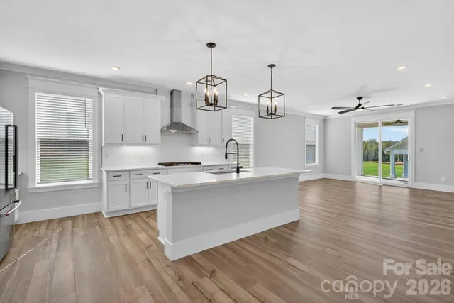 a kitchen with stainless steel appliances granite countertop a sink dishwasher a refrigerator and microwave with wooden floor