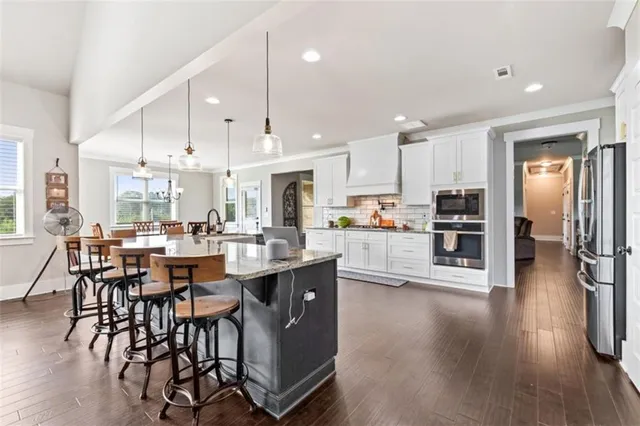 a large kitchen with cabinets wooden floor and stainless steel appliances