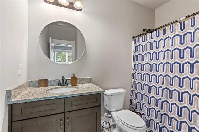 a bathroom with a granite countertop toilet and a sink