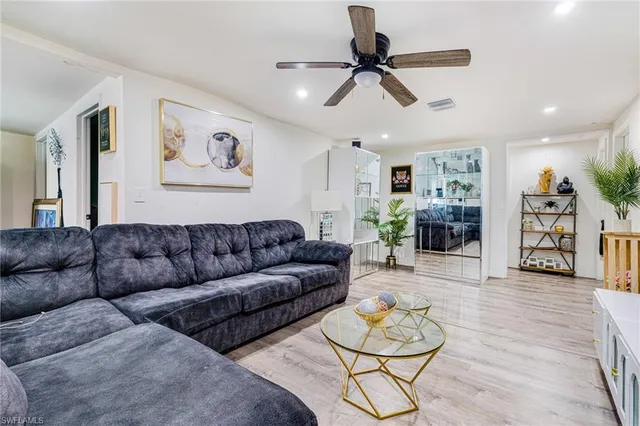 a living room with furniture kitchen view and a wooden floor