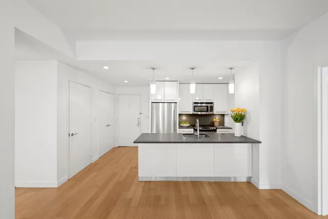 a large kitchen with stainless steel appliances a large counter top and a wooden floor