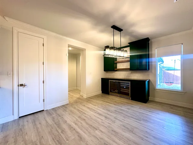 an empty room with wooden floor windows and a kitchen view