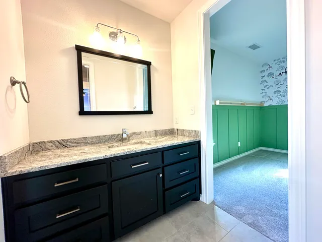 a bathroom with a granite countertop sink and a mirror