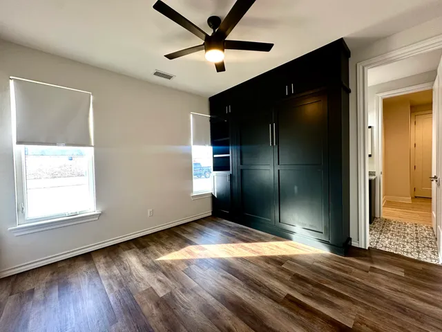 a view of empty room with wooden floor and fan