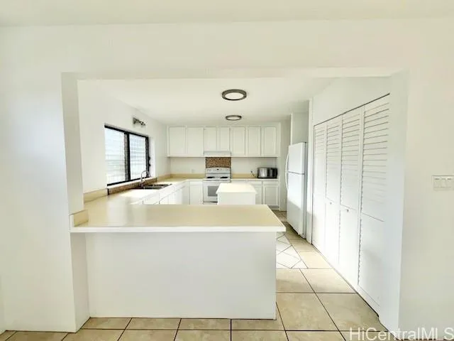 a large white kitchen with stainless steel appliances a sink and a refrigerator