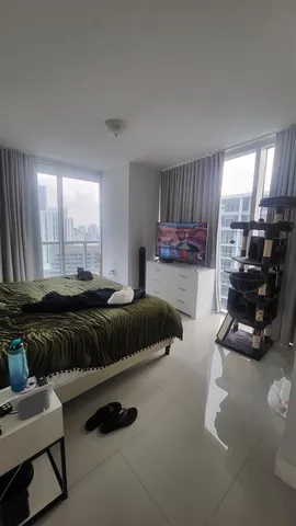 a bedroom with a bed a couch and large window