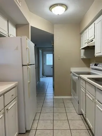 a kitchen with a refrigerator a stove top oven and cabinets