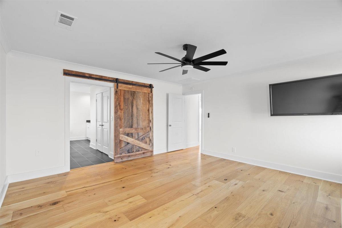 620 Diffee Road Moscow, TN 38057 - Photo 13 of 40 Unfurnished living room featuring a barn door, light wood-style floors, a ceiling fan, and crown molding