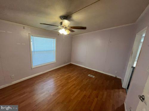 1024 Warm Spring Road, Unit 64 Greencastle, PA 17225 - Photo 4 of 8 an empty room with wooden floor fan and windows