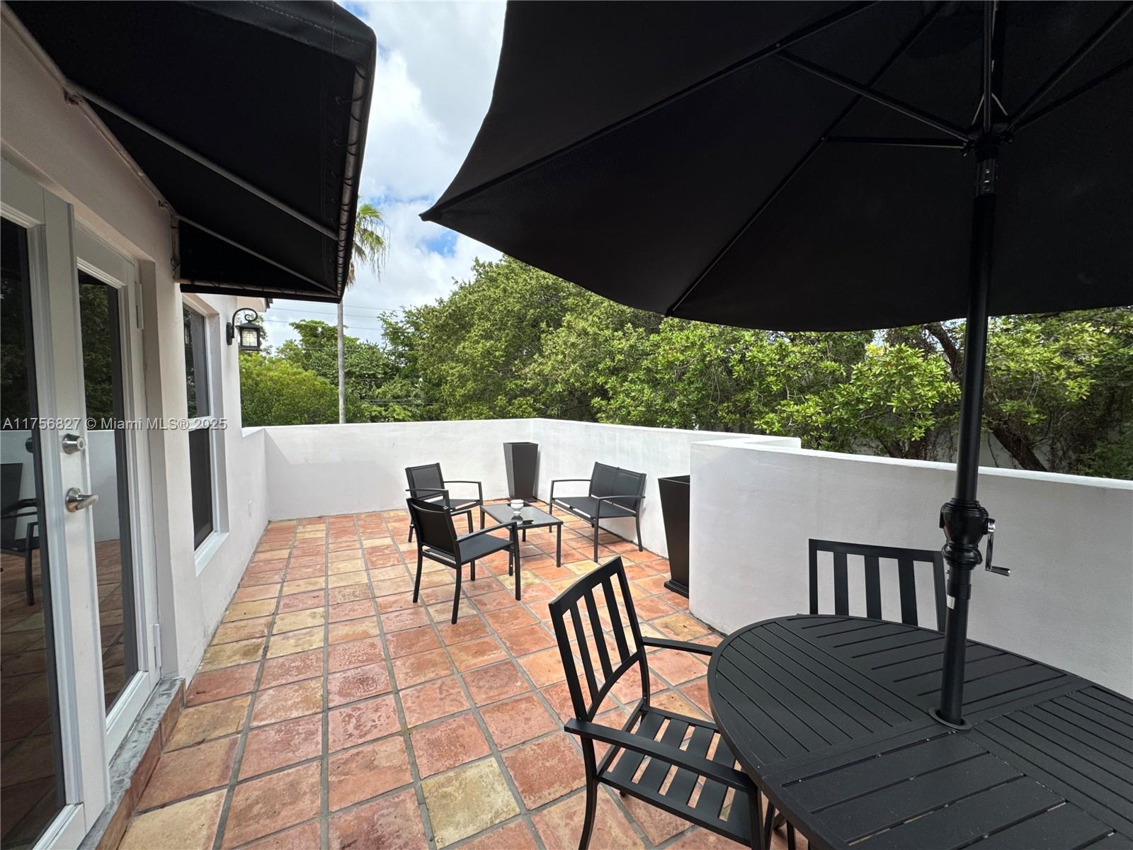 2918 Bird Avenue, Unit 8 Miami, FL 33133 - Photo 4 of 11 a view of a patio with table and chairs under an umbrella