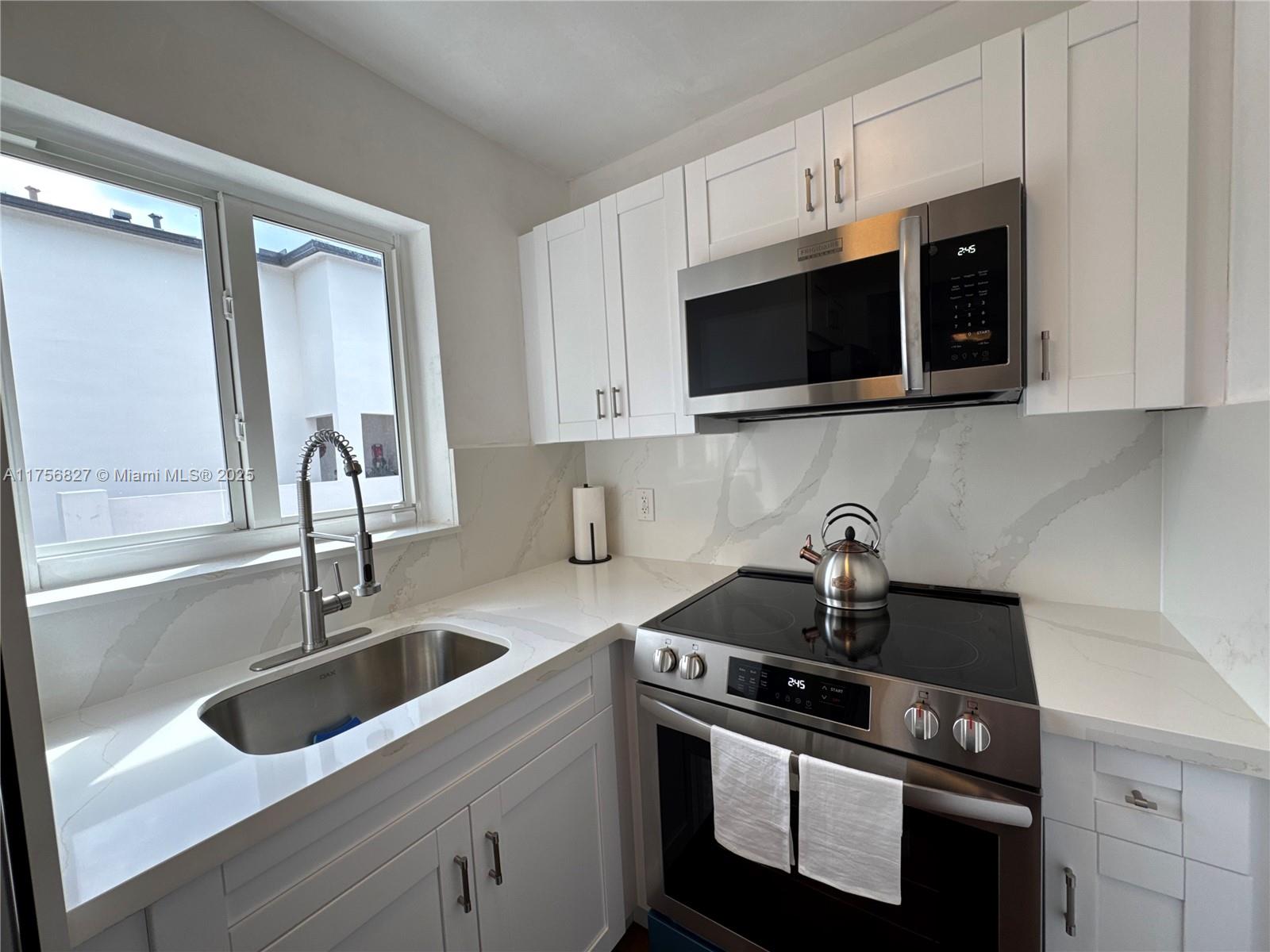 2918 Bird Avenue, Unit 8 Miami, FL 33133 - Photo 5 of 11 a kitchen with stainless steel appliances granite countertop a sink stove and microwave