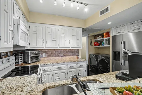 a kitchen with granite countertop white cabinets and white appliances