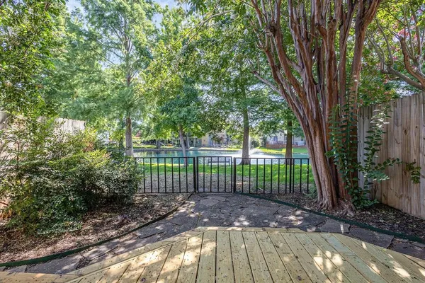 a view of a yard with large trees and a wooden fence