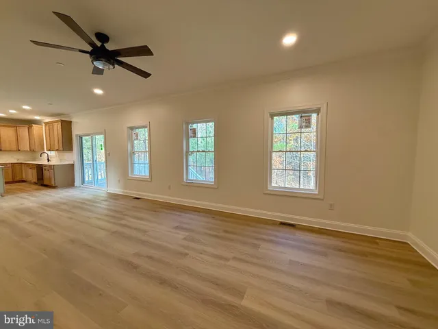 a view of an empty room with a window and a kitchen