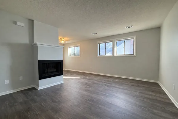 an empty room with wooden floor and fireplace