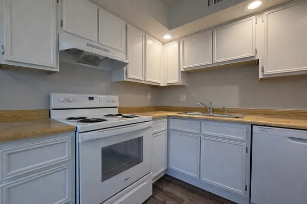 a kitchen with granite countertop white cabinets and white appliances