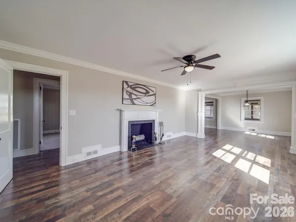 a view of a livingroom with a fireplace a ceiling fan and window